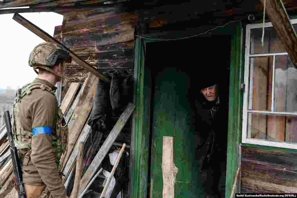 Военный 10-й отдельной горно-штурмовой бригады &quot;Эдельвейс&quot; Никита Шандиба уговаривает 82-летнего мужчины Валентина покинуть опасную зону. В марте 2022 года село Тетеревское в Киевской области наполовину сравняли с землей. Дом Валентина был частично поврежден обстрелами. Когда военные и журналисты случайно увидели силуэт мужчины и зашли внутрь, русская артиллерия начала обстрел. Валентин не хотел покидать дом, в котором прожил 50 лет, но его удалось уговорить эвакуироваться. Село Тетеревское, Киевщина, март 2022 года / Фото справа сделано в марте 2024 года